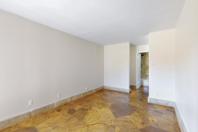 empty room featuring baseboards and stone finish floor