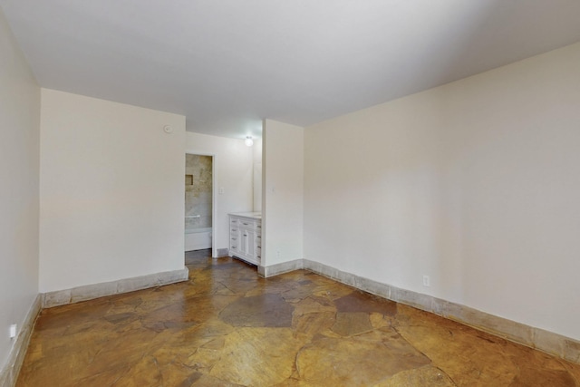 spare room featuring stone finish floor and baseboards