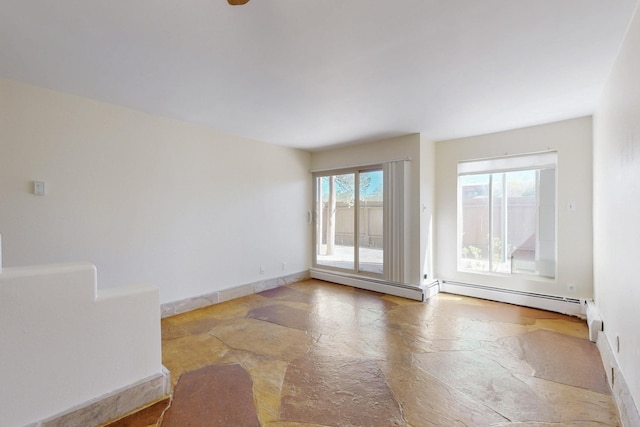 spare room with baseboards, a baseboard heating unit, and stone tile flooring