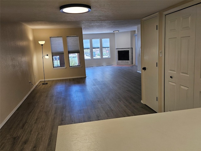 unfurnished living room with baseboards, dark wood-style floors, and a fireplace