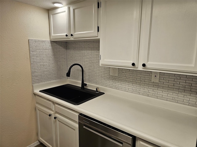 kitchen featuring a sink, dishwasher, light countertops, white cabinetry, and backsplash