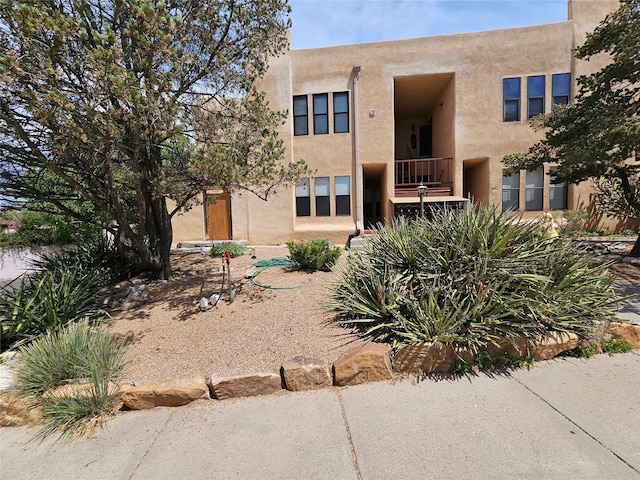 back of house with a balcony and stucco siding