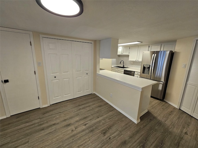kitchen featuring a sink, dishwasher, light countertops, dark wood-type flooring, and stainless steel refrigerator with ice dispenser