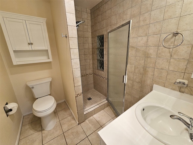bathroom with a stall shower, a sink, baseboards, tile patterned floors, and toilet