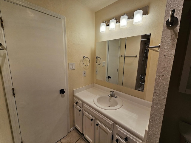 bathroom with vanity, a textured wall, and tile patterned flooring