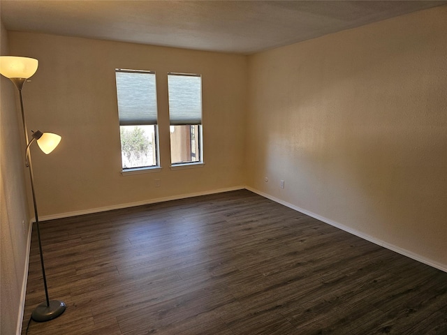 empty room featuring baseboards and dark wood-style floors