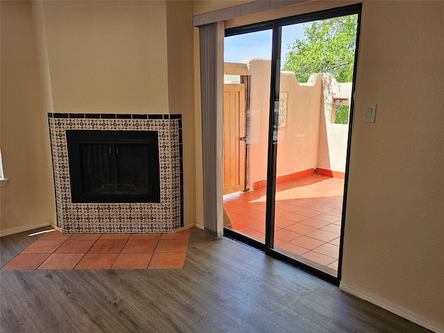 doorway to outside featuring baseboards, wood finished floors, and a tile fireplace