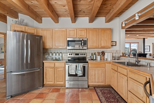 kitchen featuring appliances with stainless steel finishes, tile counters, beamed ceiling, and light brown cabinets