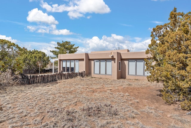 back of property with fence and stucco siding