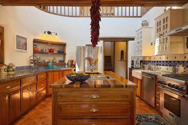 kitchen featuring a kitchen island with sink, stainless steel appliances, a sink, and tasteful backsplash