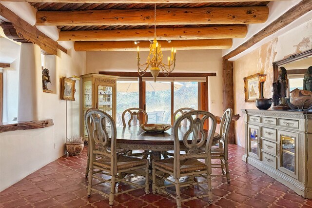 dining space with a notable chandelier, dark tile patterned flooring, and beamed ceiling