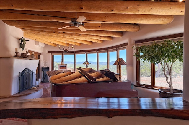 living room with a fireplace with raised hearth, beam ceiling, and ceiling fan with notable chandelier
