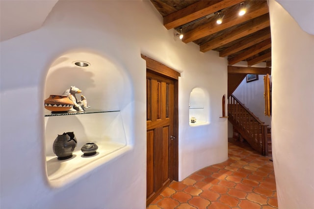 corridor with light tile patterned flooring, stairway, and beamed ceiling