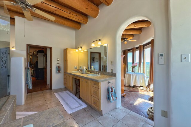 ensuite bathroom with tile patterned floors, a towering ceiling, ceiling fan, and beam ceiling