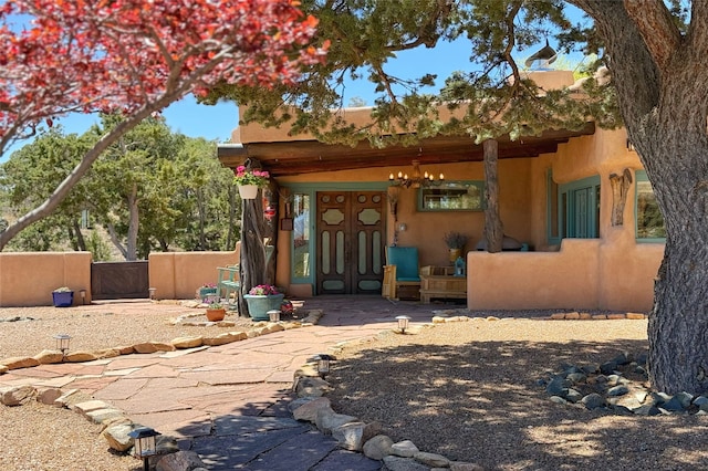 rear view of house with a gate, stucco siding, and covered porch