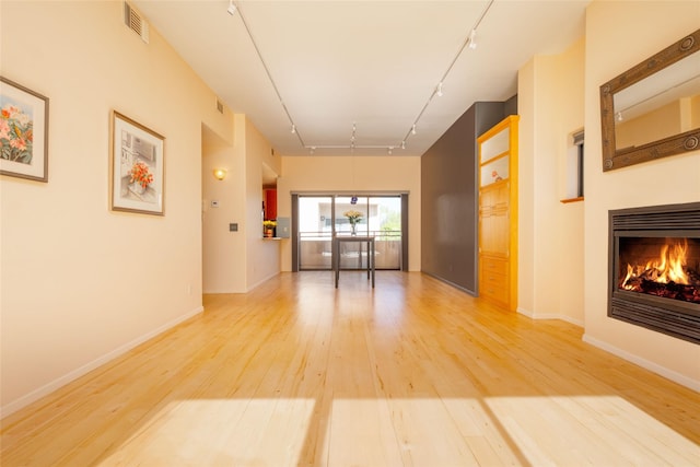 hallway featuring track lighting, light wood-style floors, baseboards, and visible vents
