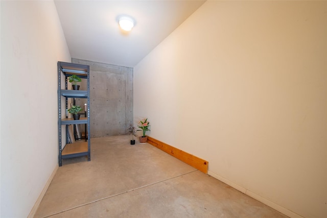 hall featuring baseboards and concrete floors