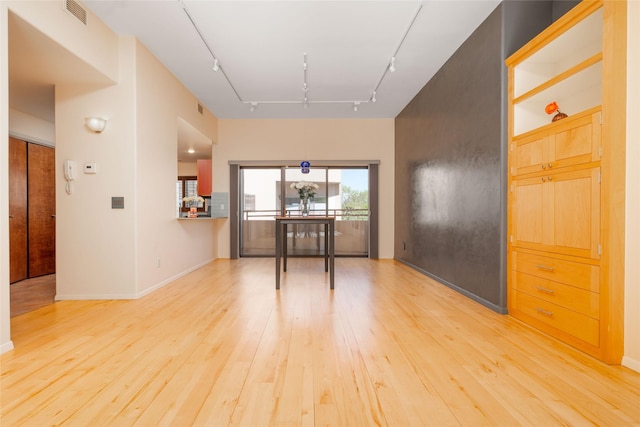 spare room featuring track lighting, light wood finished floors, baseboards, and visible vents