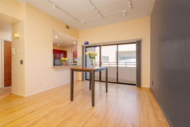 unfurnished office with track lighting, attic access, light wood-style flooring, and baseboards