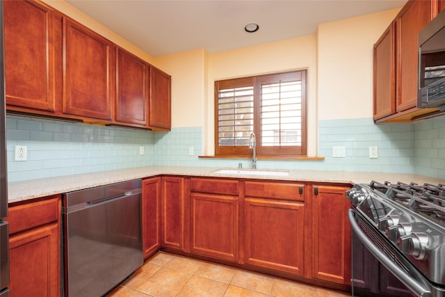 kitchen with a sink, light tile patterned floors, stainless steel appliances, and light stone counters