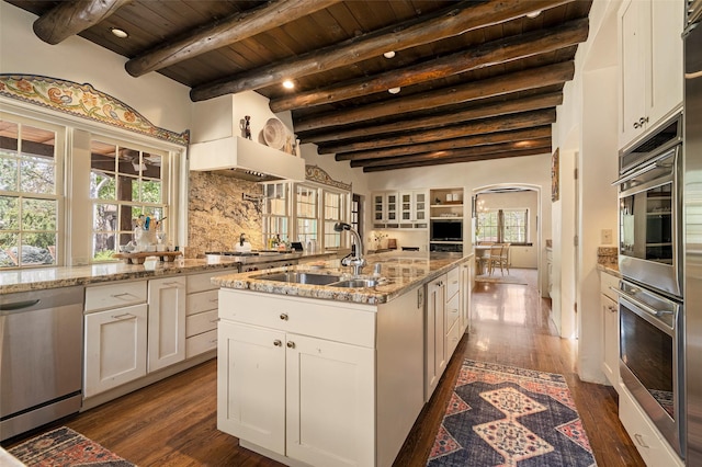 kitchen featuring arched walkways, white cabinets, wooden ceiling, a sink, and appliances with stainless steel finishes