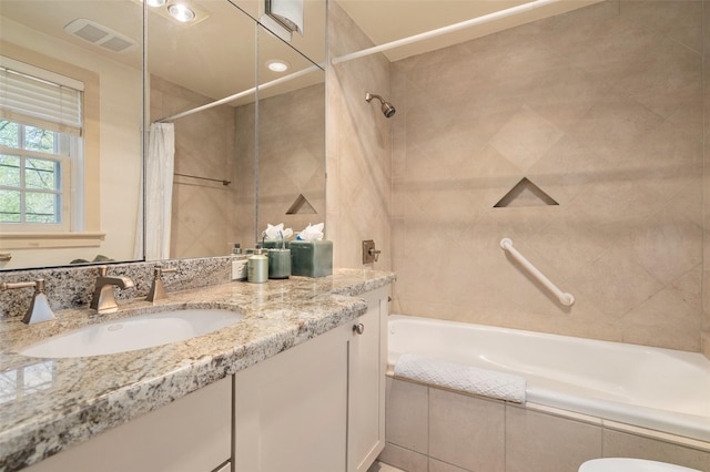 bathroom with vanity, tiled shower / bath, and visible vents