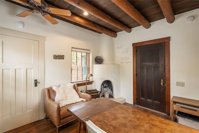 living area with dark wood-type flooring, ceiling fan, beam ceiling, and wooden ceiling