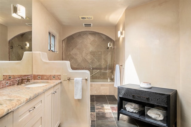 full bathroom with vanity, decorative backsplash, tiled shower / bath combo, and visible vents