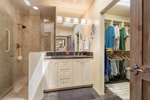 bathroom with a walk in shower, a walk in closet, and vanity