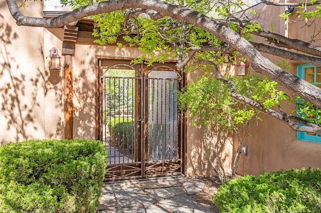 entrance to property featuring a gate and stucco siding