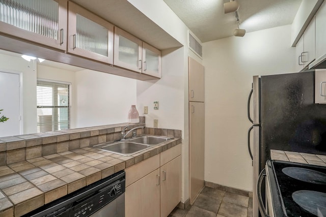 kitchen with tile countertops, appliances with stainless steel finishes, a sink, baseboards, and glass insert cabinets