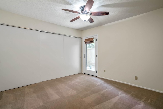 unfurnished bedroom featuring a closet, ceiling fan, carpet flooring, and a textured ceiling