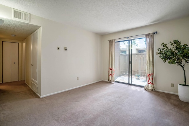 carpeted spare room featuring a textured ceiling, visible vents, and baseboards