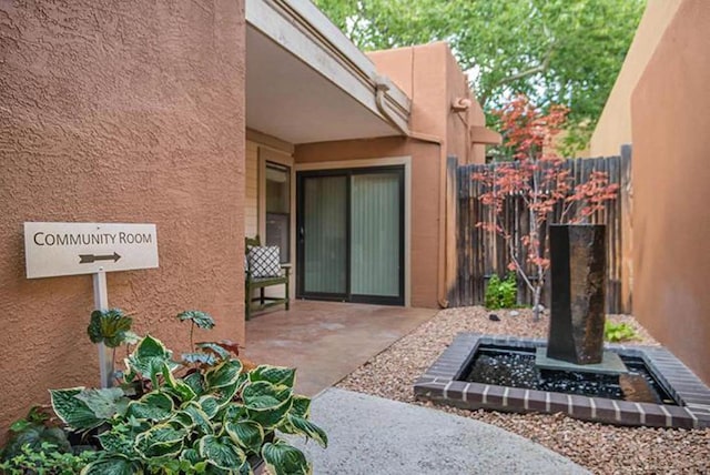 entrance to property with fence, a patio area, and stucco siding
