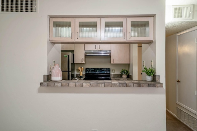 kitchen featuring freestanding refrigerator, under cabinet range hood, visible vents, and black range with electric stovetop