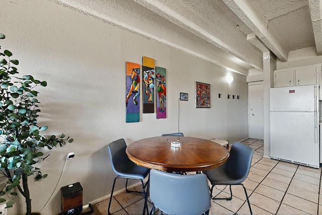 dining area featuring light tile patterned floors, baseboards, and a textured ceiling