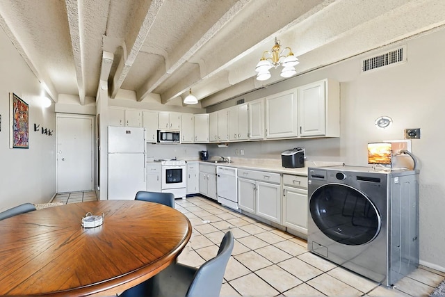 kitchen featuring visible vents, light tile patterned floors, a sink, washer / dryer, and white appliances