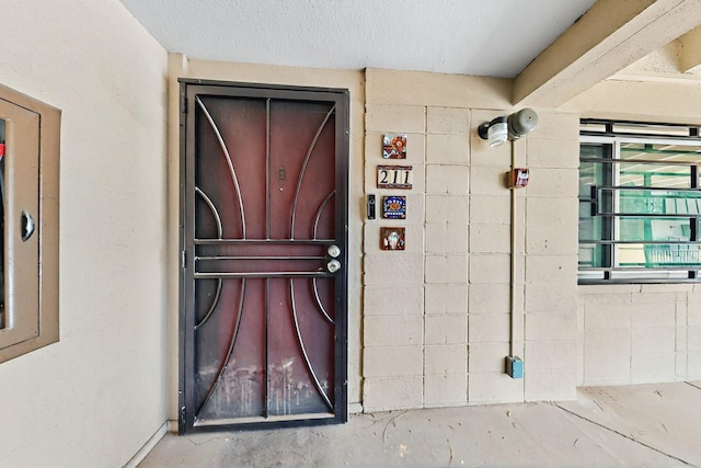 view of exterior entry with concrete block siding and stucco siding