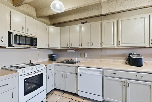 kitchen with white appliances, light tile patterned floors, a sink, and light countertops