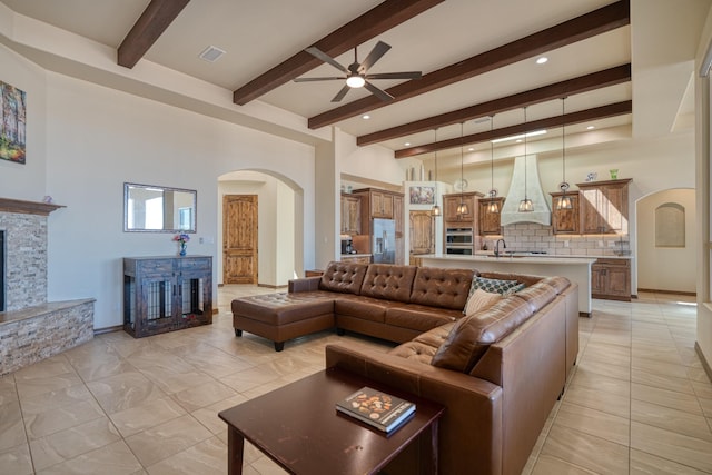 3415 Ramadan Ct NE, Rio Rancho, NM 87144 - living area with ceiling fan, a fireplace, arched walkways, beamed ceiling, and visible vents