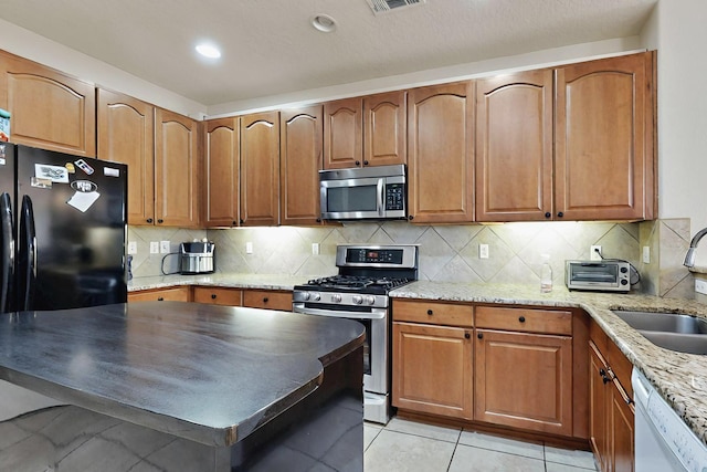4359 San Benito St Unit B, Santa Fe, NM 87507 - kitchen with appliances with stainless steel finishes, brown cabinets, light stone countertops, and a sink