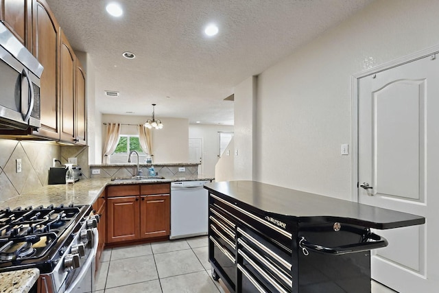 4359 San Benito St Unit B, Santa Fe, NM 87507 - kitchen featuring a sink, brown cabinetry, light stone countertops, appliances with stainless steel finishes, and tasteful backsplash