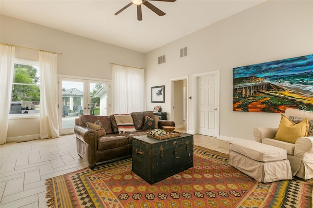 living room featuring a high ceiling, baseboards, a ceiling fan, and visible vents