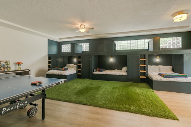 game room featuring a textured ceiling, a ceiling fan, and wood finished floors