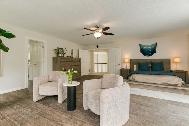 bedroom featuring ceiling fan, a textured ceiling, baseboards, and wood finished floors