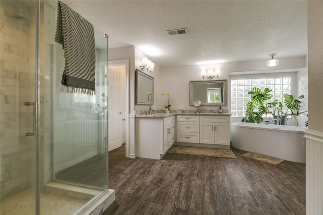 full bathroom with wood finished floors, vanity, visible vents, a shower stall, and a freestanding bath