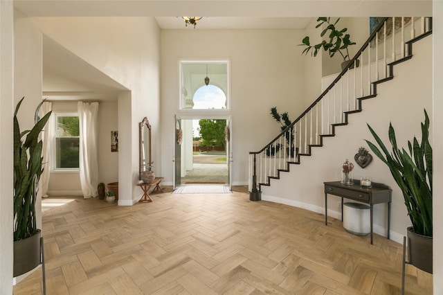 entryway with stairs, a high ceiling, baseboards, and a healthy amount of sunlight