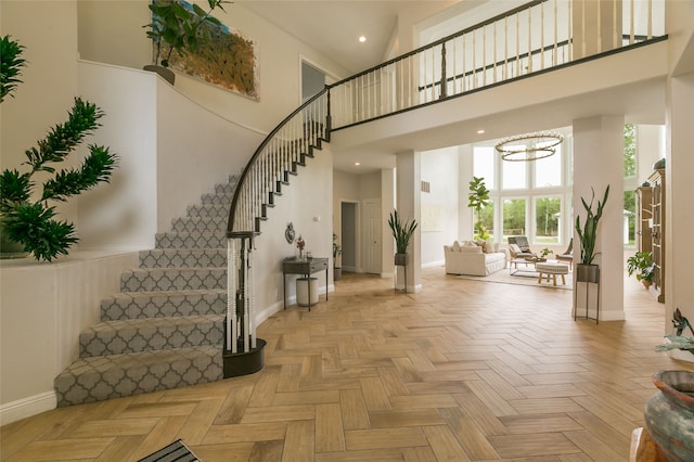 entrance foyer with stairs, a high ceiling, baseboards, and a notable chandelier