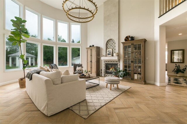 living area featuring a chandelier, baseboards, a high ceiling, and recessed lighting