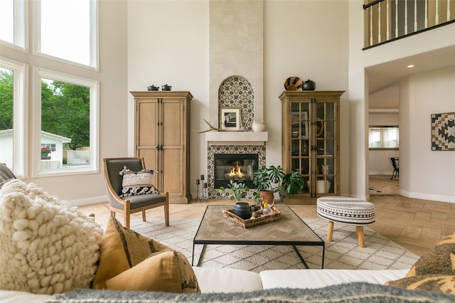 living room with a towering ceiling, baseboards, and a tile fireplace